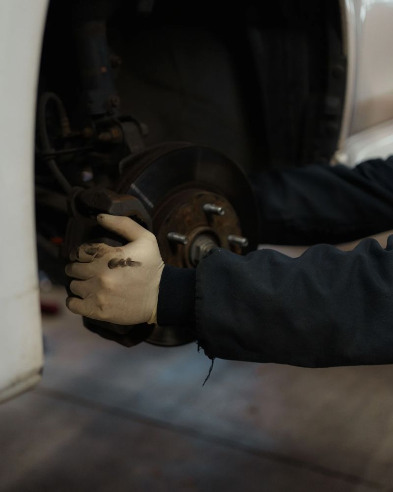 Gloved hand fitting a brake caliper over the rotor
