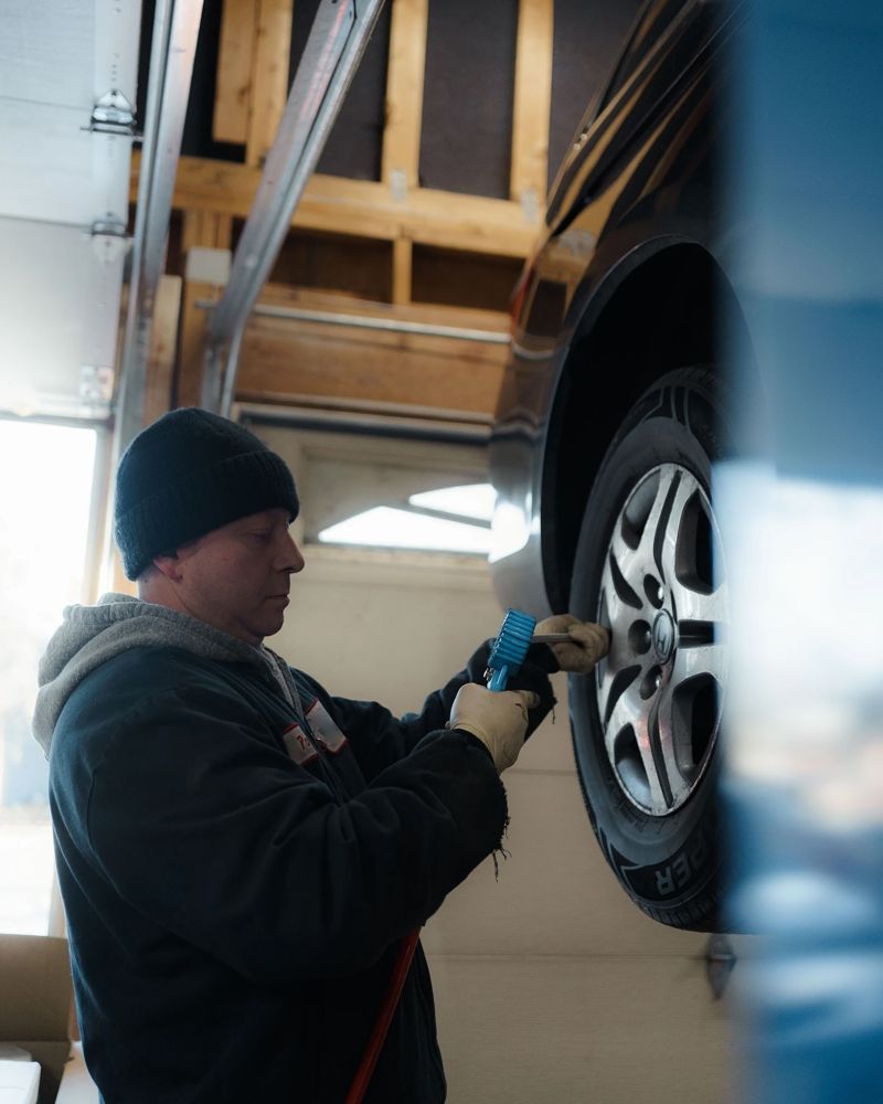 Mechanic checking tire pressure on a Honda raised on the lift